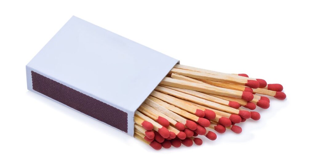 A white rectangular matchbox filled with several wooden matches with red tips on a white background.