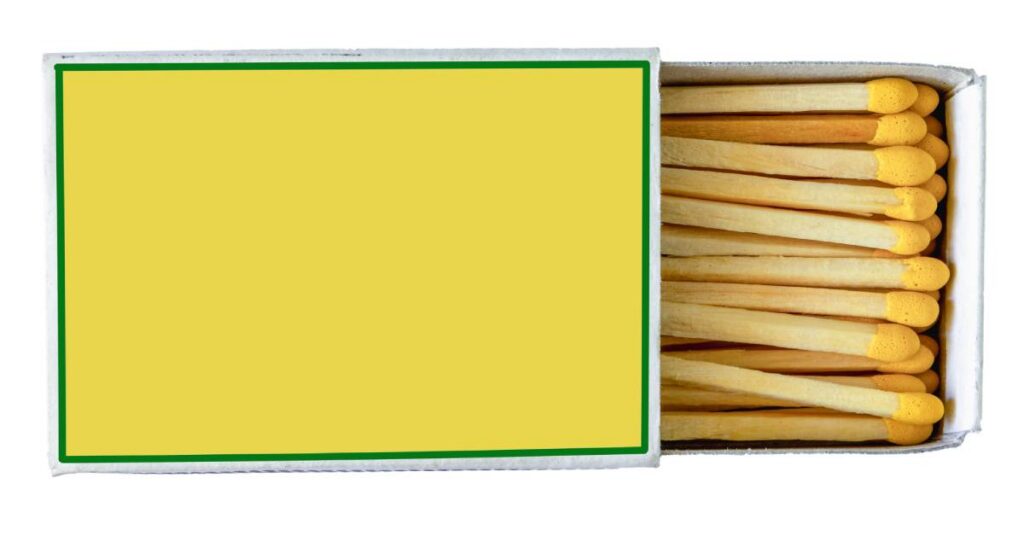 An open matchbox with a yellow label on the cover and wooden matches with yellow tips arranged inside the sliding tray.