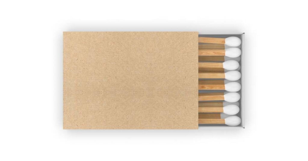 A partially open cardboard matchbox with wooden matches arranged in rows against a plain white background.